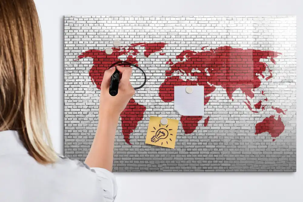 Tablă cu marker cu design de contur al continentelor pe fundal de cărămidă