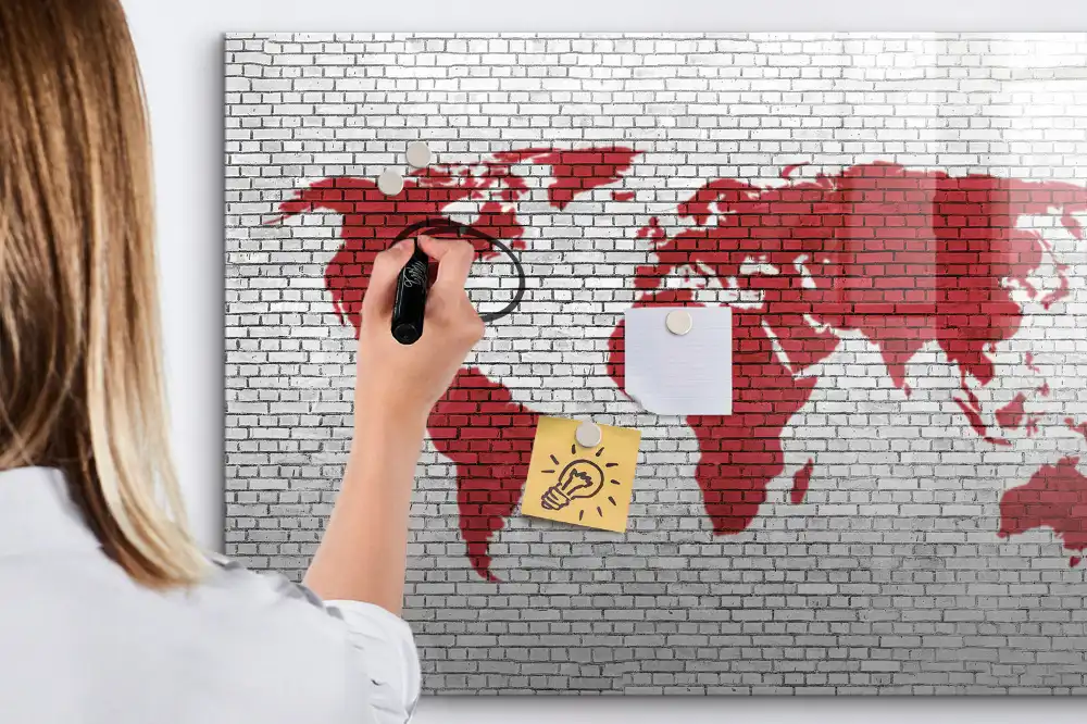 Tablă cu marker cu design de contur al continentelor pe fundal de cărămidă