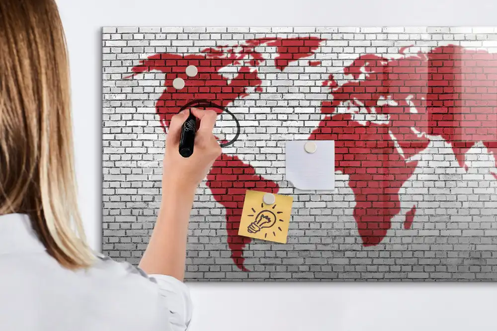 Tablă cu marker cu design de contur al continentelor pe fundal de cărămidă