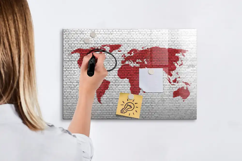 Tablă cu marker cu design de contur al continentelor pe fundal de cărămidă